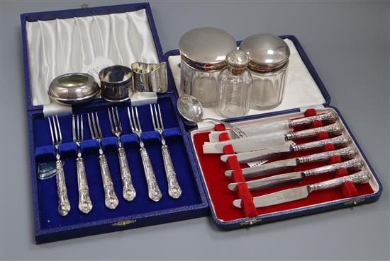 Two cased sets of silver handled tea knives and forks, three mounted toilet jars, two napkin rings, a sifter spoon and pot.